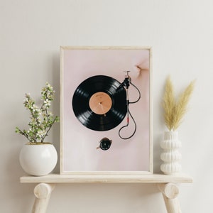 May include: A framed print of a black vinyl record on a turntable with a pink background.