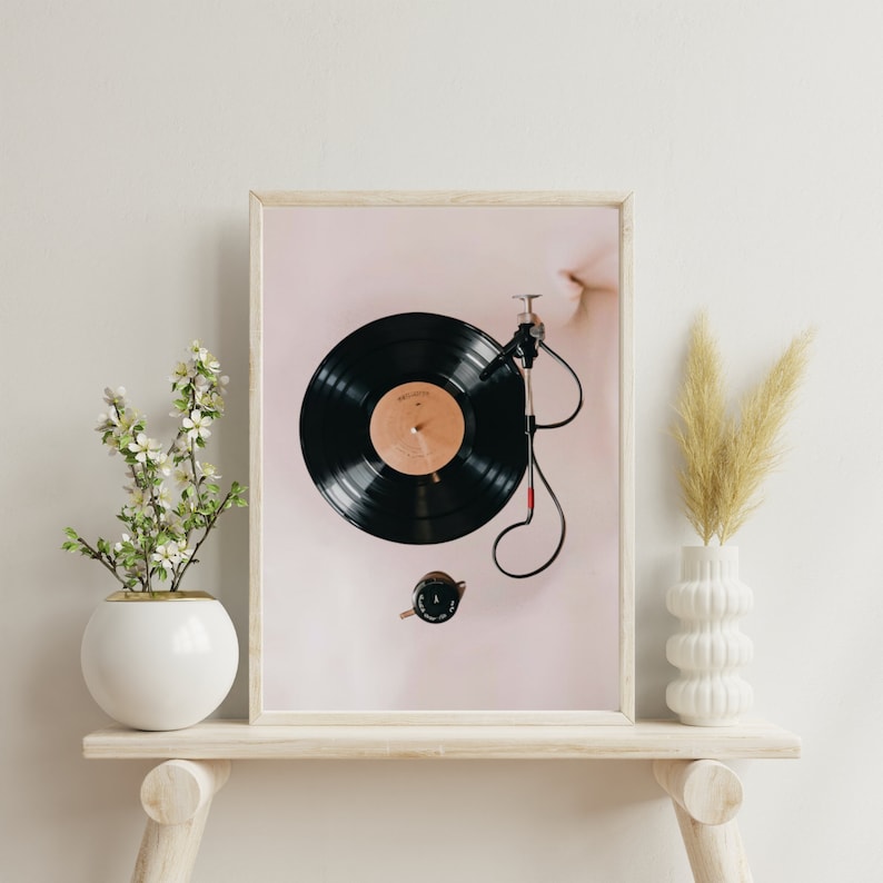 May include: A framed print of a black vinyl record on a turntable with a pink background.