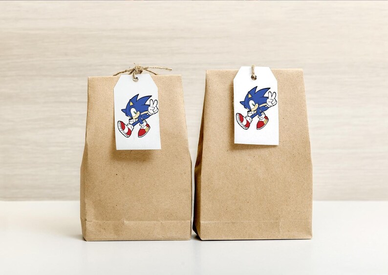 May include: Two brown paper gift bags with white tags. Each tag has a cartoon image of Sonic the Hedgehog, a blue hedgehog with red shoes, running and giving a peace sign.