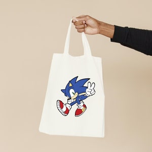 May include: White tote bag with a blue and red cartoon image of Sonic the Hedgehog giving a peace sign.