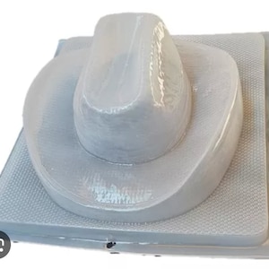 Puede incluir: Un molde de plástico gris para hacer un sombrero de vaquero. El molde es texturizado y tiene un diseño en relieve.