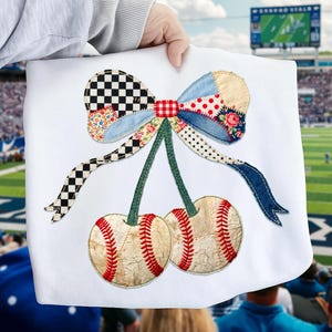 Puede incluir: Tela blanca con un diseño temático de béisbol. El diseño presenta dos pelotas de béisbol con costuras rojas, conectadas por tallos verdes a un lazo de patchwork con varios patrones, incluyendo cuadros, flores y lunares. El lazo tiene detalles de mezclilla azul.