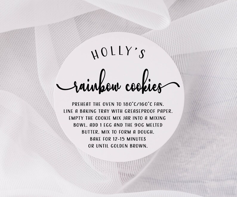 May include: A white circular sticker with black text that reads "HOLLY'S rainbow cookies". The sticker includes instructions for baking rainbow cookies, including preheating the oven to 180&deg;C/160&deg;C fan, lining a baking tray with greaseproof paper, adding an egg and melted butter to the cookie mix, and baking for 12-15 minutes.