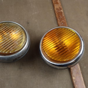 Puede incluir: Dos luces de coche redondas, cromadas, de color ámbar con una lente acanalada.