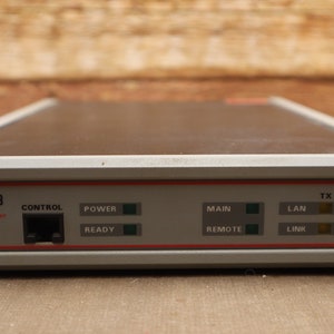 May include: A gray and black RAD MBE-8 LAN/RAN device with a control panel featuring a network port, power and ready lights, and a main and remote switch. The device also has a LAN link light and TX, RX, and ERR lights.