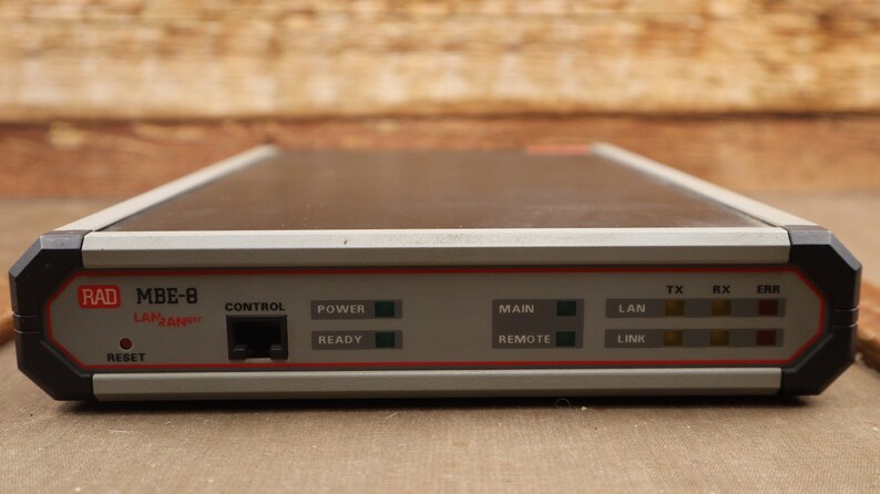 May include: A gray and black RAD MBE-8 LAN/RAN device with a control panel featuring a network port, power and ready lights, and a main and remote switch. The device also has a LAN link light and TX, RX, and ERR lights.