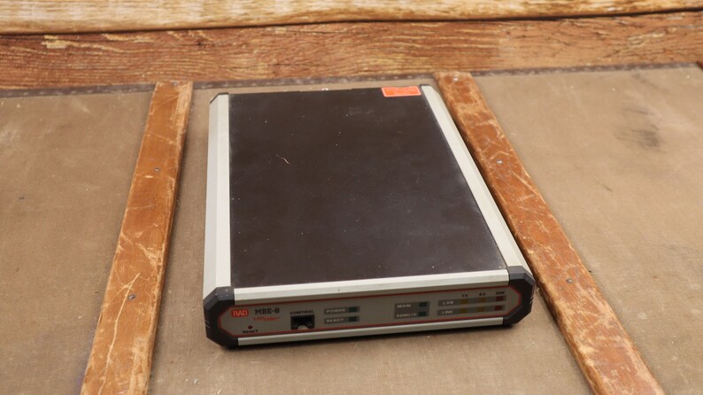 May include: A black and silver electronic device with the text "RAD MBD-8" on the front. The device has several buttons and lights.