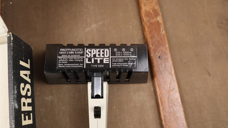 May include: Black Speed Lite Type 1000 flash unit with a white power switch and a label that reads "Inkkopplingstid Max 5 Min 5 Amp Made in Denmark 220 v 1000 w 240 v 1000 w. Vid lampbyte dra f&ouml;rst ur stickkontakten Trak str&ouml;mkabeln ur f&ouml;rst ur stickkontakten af lampan."