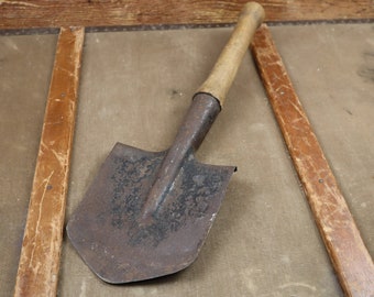 May include: A rusty metal shovel with a wooden handle. The shovel is lying on a wooden surface.