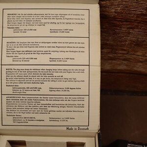 May include: Close-up of a white box with black text containing instructions and warnings for a product. The text is in Danish and includes the words "Bem&aelig;rk", "Note", and "Anmerkung". The box also has the words "Made in Denmark" printed on the bottom.