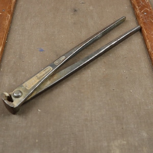 Può includere: Un paio di pinze in metallo arrugginito con un'etichetta in ottone che recita "Made in England".