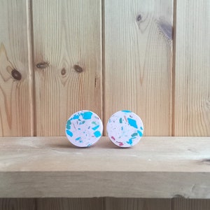 Op de afbeelding: Twee ronde terrazzo-ladegrepen in roze en wit met blauwe en groene vlekken.