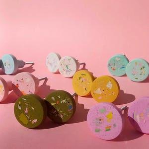 Peut inclure: Assortiment de boutons ronds colorés pour armoires avec une finition mouchetée. Les boutons sont en résine et présentent une variété de couleurs, notamment le rose, le bleu, le vert, le jaune et le marron. Chaque bouton est doté d'une vis argentée.