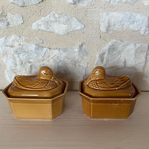 Puede incluir: Dos platos de servir de cerámica marrón en forma de pato con tapas. Los platos están esmaltados y tienen un aspecto rústico.
