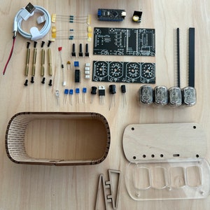 May include: A DIY kit for building a clock using vintage-style Nixie tubes. The kit includes a wooden case, a circuit board, Nixie tubes, resistors, capacitors, and other components. The kit also includes a USB cable for power.