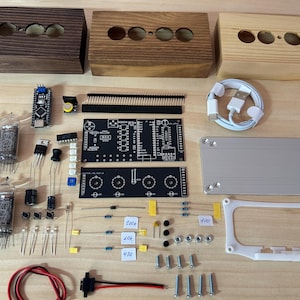 Könnte beinhalten: Eine Auswahl an elektronischen Komponenten und Holzgehäusen für ein DIY-Projekt. Enthält Leiterplatten, Vakuumröhren, Widerstände und ein USB-Kabel. Die Holzboxen haben Löcher für Anzeigekomponenten.