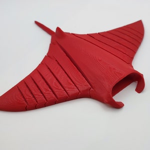 Puede incluir: Una escultura de raya manta roja impresa en 3D con una superficie texturizada detallada.