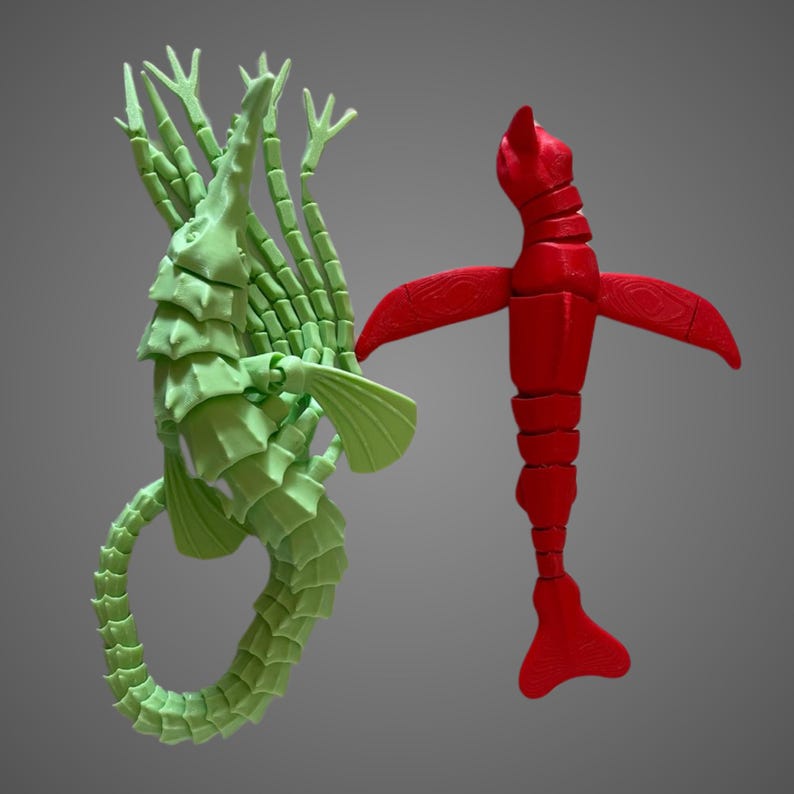 May include: Two 3D printed sea creatures, one green and one red. The green creature is a seahorse with multiple arms and a curled tail. The red creature is a fish with a long, segmented body and fins.