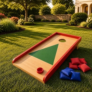 May include: A wooden cornhole board with a red frame and a green triangle design. A red bean bag and several red and blue bean bags are on the grass. Perfect for outdoor games and family fun.