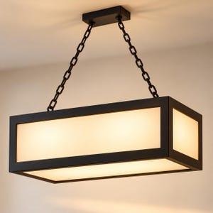 May include: A rectangular pendant light fixture featuring a matte black metal frame and frosted white glass panels. The fixture is suspended from a ceiling mount by two black metal chains, emitting a warm, diffused glow from within the structure.