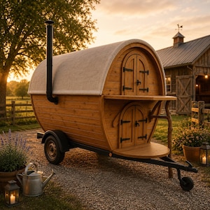 May include: A wooden barrel-shaped structure on a trailer, featuring two arched doors and a black chimney. The structure has a light-colored roof and is set against a rural backdrop with a sunset.