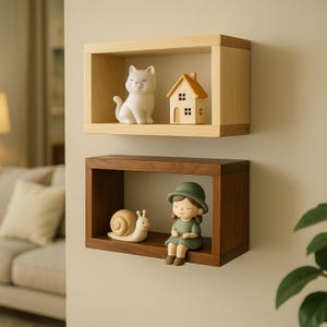 Puede incluir: Dos estantes flotantes de madera con objetos decorativos. El estante superior es de madera clara y contiene una figura de gato blanco y una casita. El estante inferior es de madera oscura y muestra un caracol y una figura de niña.