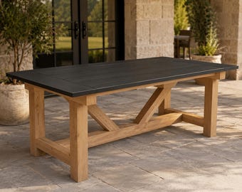 May include: A rectangular outdoor dining table with a dark grey tabletop and light brown wooden base. The table has a trestle-style base with angled supports. The table is approximately 183 cm long and 91 cm wide.