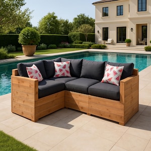 Puede incluir: Un sofá seccional de madera con un cojín de tela gris y cuatro almohadas de estampado de sandía rosa. El sofá está colocado en un patio junto a una piscina.