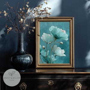 A teal botanical digital art print featuring delicate line-drawn flowers with soft, textured petals set against a smooth teal background. The artwork is displayed in a gold frame on a white paneled wall, creating a modern, elegant, nature-inspired aesthetic. Perfect for living room, bedroom, or entryway decor. Digital download floral wall art with soft teal tones and minimalistic botanical style.