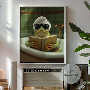 Könnte beinhalten: Gerahmter digitaler Download-Druck mit einer grünen Froschfigur in einer Badewanne, die eine Sonnenbrille und ein Handtuch auf dem Kopf trägt. Der Frosch liest ein Buch mit dem Text "JUST KEEP HOPPING". Der Druck wird über einem Vintage-Verstärker angezeigt.