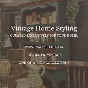 May include: A dark green wooden hutch with a natural wood top, featuring open shelves filled with various ceramic pitchers, jars, and canisters. The text reads: Vintage Home Styling, CURATED EXCLUSIVELY FOR YOUR HOME, PERSONALIZED DESIGN, AUTHENTIC VINTAGE, ONE-OF-A-KIND COLLECTIONS.