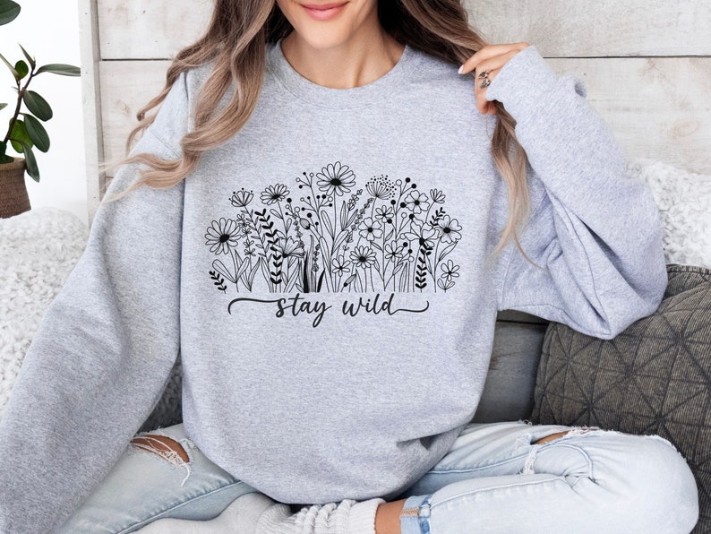 May include: A gray sweatshirt with a black floral design and the text "stay wild".