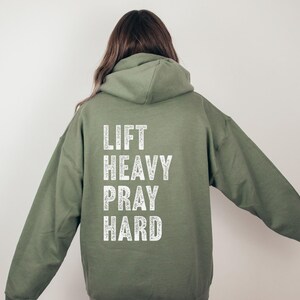 May include: A green hooded sweatshirt with the text "LIFT HEAVY PRAY HARD" printed in white on the back.