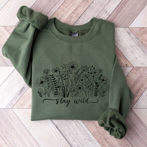 May include: A green sweatshirt with a black floral design and the text "Stay Wild".