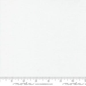 May include: A plain white fabric with a subtle texture. The fabric is shown with a ruler for scale.
