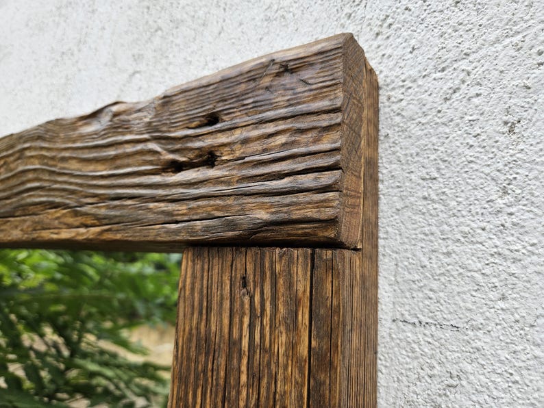May include: A rustic wooden mirror frame with a natural wood finish. The frame is made of reclaimed wood with knots and grain patterns. The mirror is rectangular and has a clear reflection.