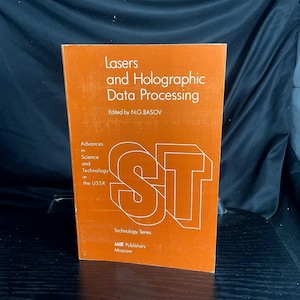 May include: An orange book titled "Lasers and Holographic Data Processing" with white text. The book is part of the "Technology Series" and published by MIR Publishers, Moscow. The cover features the letters "ST" in a bold, white outline.