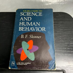 May include: A paperback book titled Science and Human Behavior by B. F. Skinner. The dark blue cover features a large brown silhouette of a human head profile and a central graphic of overlapping orange, green, and purple petal-like shapes.