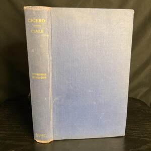 May include: A vintage book titled "Cicero" with a blue cover and gold lettering. The spine features the author's name, the title, and "Interlinear Translation." The book is in good condition, showing signs of age.