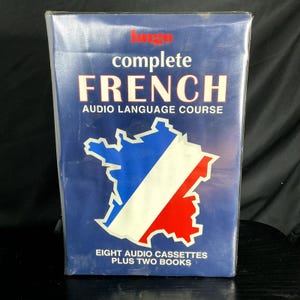 May include: A blue box set for a complete French audio language course. The box features the word "FRENCH" in large white letters, a map of France in red, white, and blue, and the text "EIGHT AUDIO CASSETTES PLUS TWO BOOKS."