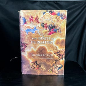 May include: A hardcover book titled "The Birth of Purgatory" by Jacques Le Goff. The cover features a Renaissance-style painting with figures in clouds and the title in large, bold letters. The book is on a dark surface.