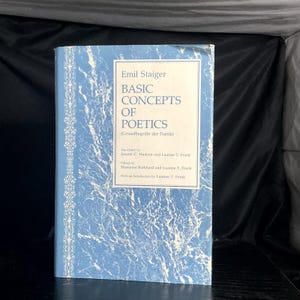 May include: A book titled "Basic Concepts of Poetics" by Emil Staiger. The cover is light blue with a marbled texture and white text. The title is in a large font, with the subtitle in parentheses. The book's spine has a decorative border.