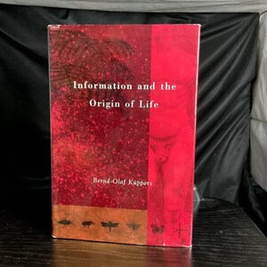 May include: A hardcover book titled "Information and the Origin of Life" by Bernd-Olaf Küppers. The cover is predominantly red with a dark, textured design and the title in white. The bottom features insect illustrations.