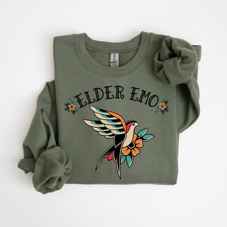 May include: A green sweatshirt with the text "ELDER EMO" and a stylized tattoo-style bird with flowers.