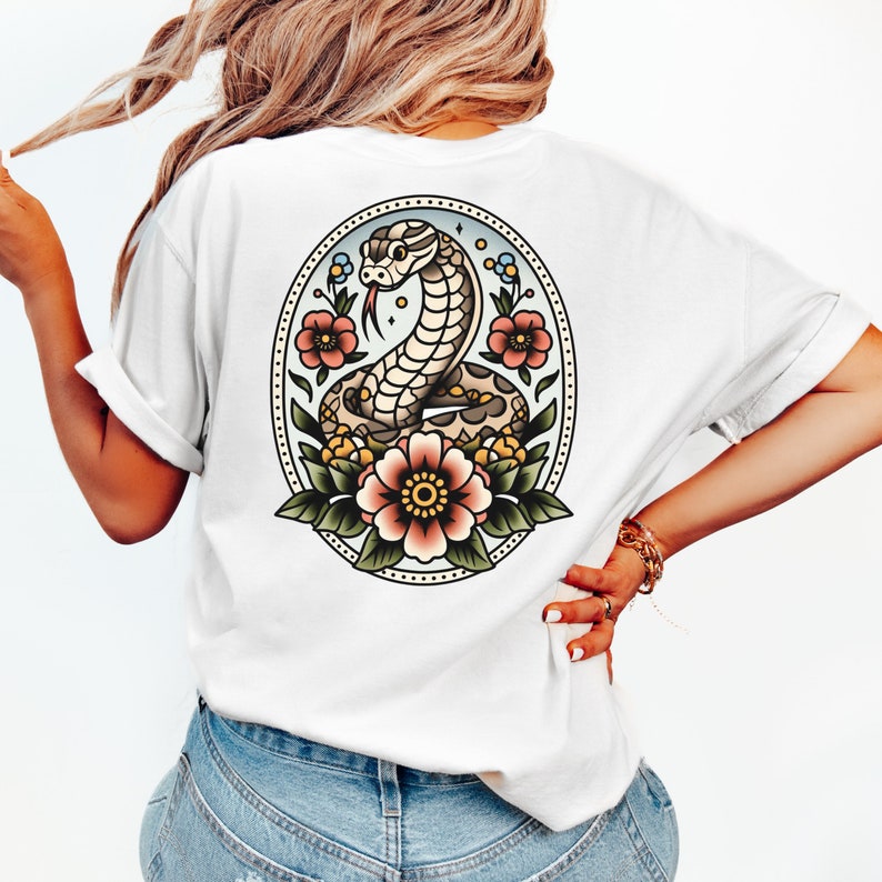 May include: White t-shirt with a vintage-style illustration of a snake with flowers on the back.