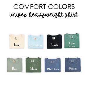May include: A set of ten unisex heavyweight t-shirts in various colors, including ivory, chambray, black, light green, bay, moss, blue jean, and denim. The shirts are folded and laid out on a white background. The text "COMFORT COLORS unisex heavyweight shirt" is displayed above the shirts.