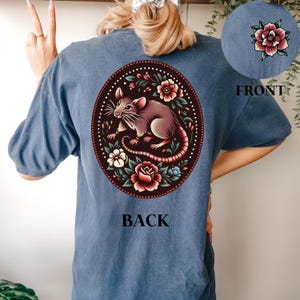 May include: A blue t-shirt with a floral design featuring a rat and the words "BACK" and "FRONT" printed on the back and front of the shirt.