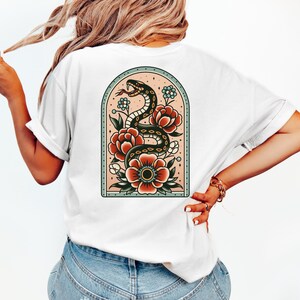 K&ouml;nnte beinhalten: Wei&szlig;es T-Shirt mit einem Tattoo-Design im Vintage-Stil auf der R&uuml;ckseite. Das Design zeigt eine schwarze Schlange, die sich um rote und wei&szlig;e Blumen in einem hellblauen Bogen windet.