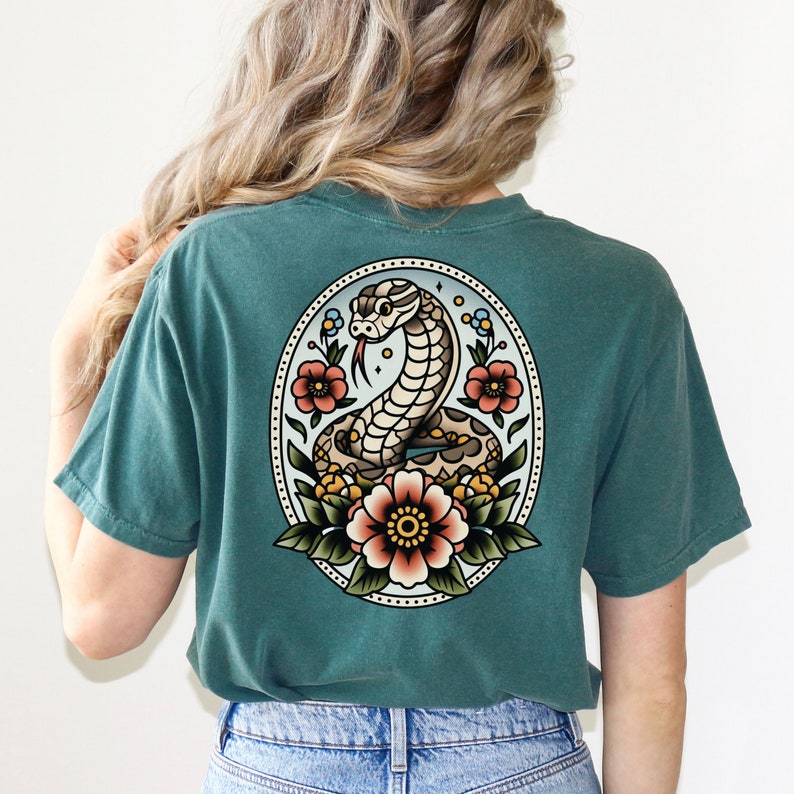 May include: A teal blue t-shirt with a vintage style tattoo design of a snake with flowers on the back.