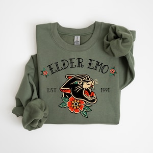 May include: A green sweatshirt with a black panther graphic and the text "ELDER EMO EST 1991".